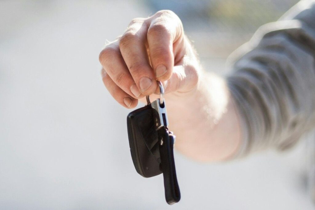 A new car key next to a key fob on a white background, symbolizing car key replacement services.